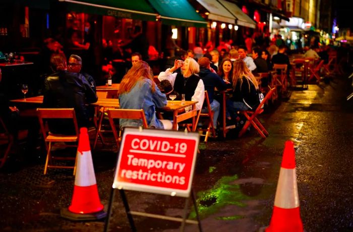 People enjoy drinks outside a cafe in Soho, central London, on September 23.