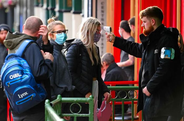 On October 2, a security guard checks the temperature of customers at a bar in Liverpool, north-west England.