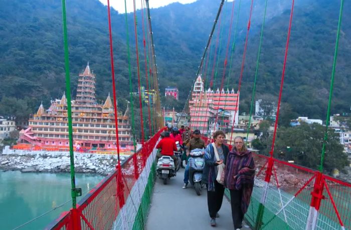 Pedestrians and vehicles share a narrow path on Lakshman Jhula.