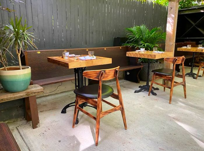 Claro’s backyard is a lush, serene space with socially distanced tables, offering an ideal setting for outdoor dining.