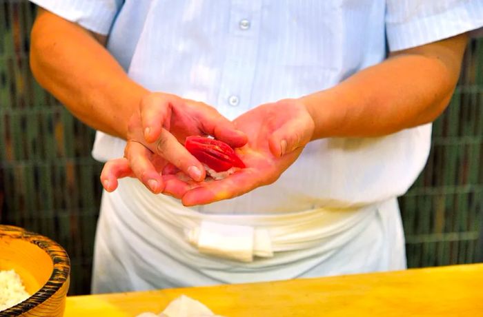 A sushi chef meticulously prepares a dish.