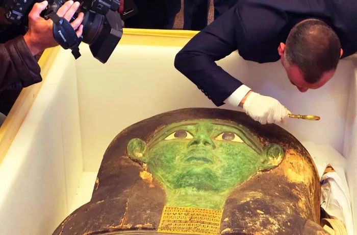 Mostafa Waziri of the Supreme Council of Antiquities inspects the ancient wooden sarcophagus with a magnifying glass during a handover ceremony at Cairo's Foreign Ministry on Monday.