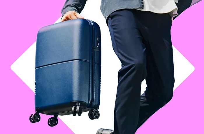 A man carrying a dark blue suitcase while dressed in black pants