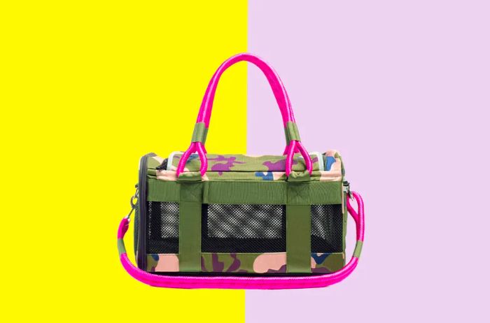 A rectangular pet carrier in a green camo print with hot pink straps