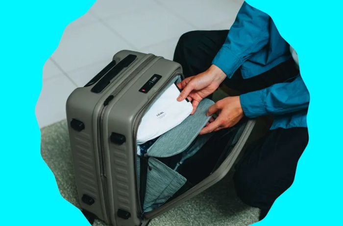 Person holding item in an open suitcase