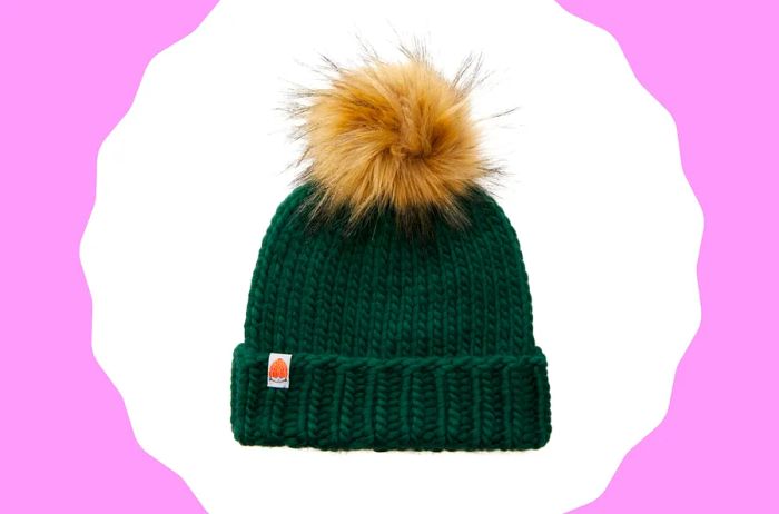 Forest green hand-knit beanie with a fluffy beige pom-pom