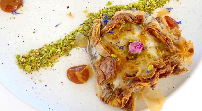 The traditional galatopita, a milk pie, was elegantly presented with crunchy Greek pistachios and a delicate rosebud garnish.