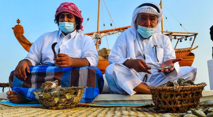 During the Katara Traditional Dhow Festival, Qatari men dive into oysters to retrieve pearls, showcasing their skills.