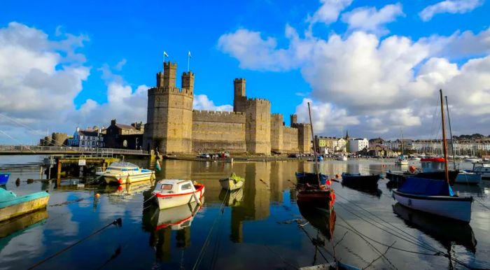 Caernarfon Castle, a striking royal fortress-palace, stands proudly on the banks of the River Seiont in Wales, offering a dramatic glimpse into the country’s royal history.