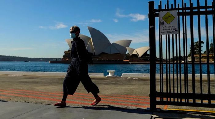 On July 13, 2021, a pedestrian wearing a face mask walks past the iconic Sydney Opera House, as the city enters lockdown to contain a rapidly escalating coronavirus outbreak.