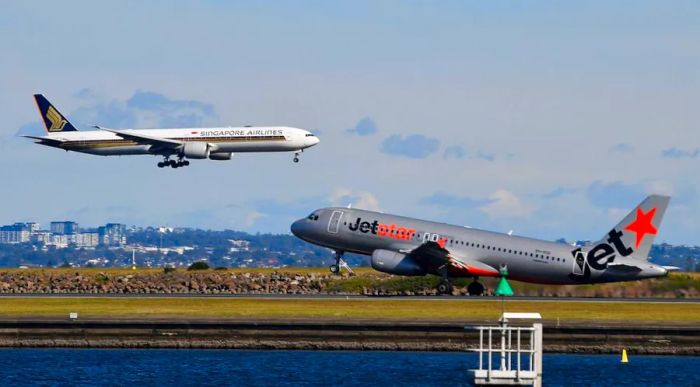 A Singapore Airlines flight touches down next to a departing Jetstar aircraft at Sydney Airport on June 4, 2021.