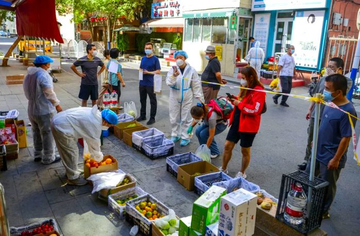 On September 5, residents gather behind a cordon at a fruit stall in the Tianshan district of Urumqi, Xinjiang, China.