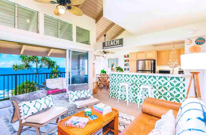 A vibrant living room and kitchen featuring white and green tiles, a leather sofa, two chairs, and a ceiling fan.