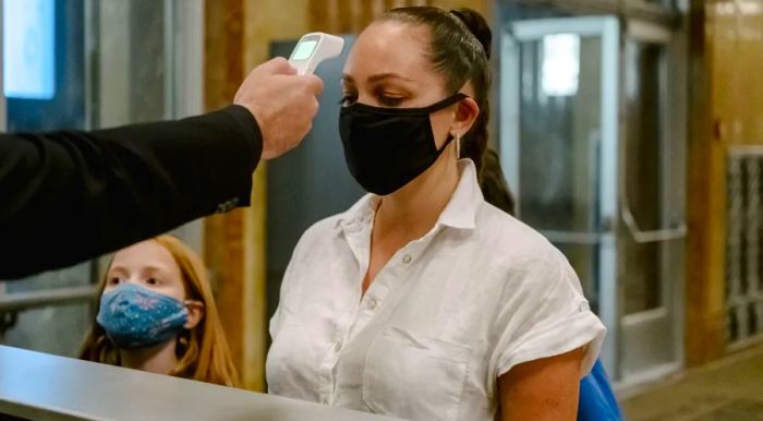 A staff member checks the temperature of customers arriving for indoor dining at Crown Shy restaurant in New York.