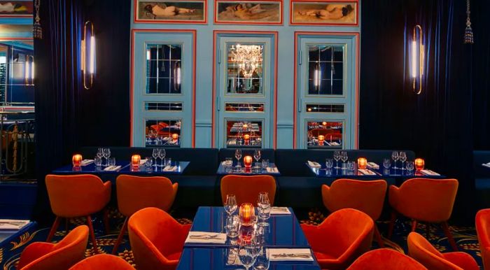 Froufrou’s interior is as dramatic as its name, featuring deep velvet midnight blue curtains that contrast beautifully with brass accents and mirrored walls, evoking the opulence of the Belle Époque, the era when theater culture first flourished.