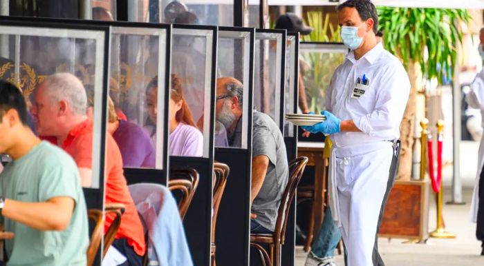 A waiter in a face mask and rubber gloves stands outside Peter Luger Steakhouse in Brooklyn.