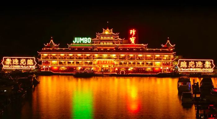 As night falls, Jumbo Kingdom casts a brilliant glow over Hong Kong's Aberdeen Harbor, creating a mesmerizing spectacle.