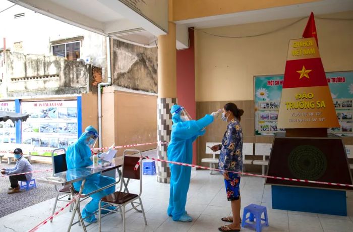 A health worker checks the temperature of a member of the public at a Covid-19 vaccination center in Ho Chi Minh City on August 5, 2021.