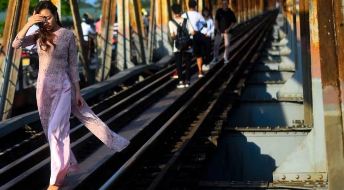 A Vietnamese woman strolls across the historic Long Bien Bridge in Hanoi, a century-old landmark.