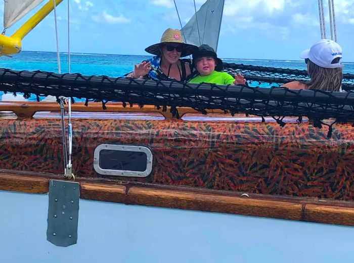 Mathias Pascal and his mother, Aline, enjoy a scenic boat ride on a traditional vessel in Moorea, French Polynesia.