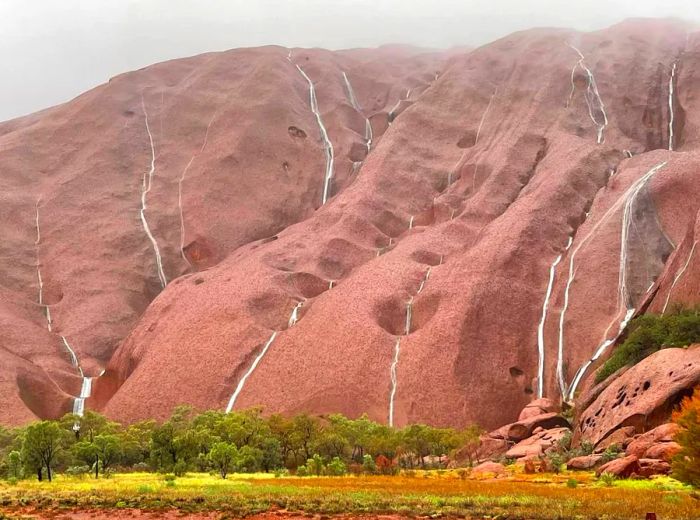 A series of waterfalls cascade down the face of Uluru.