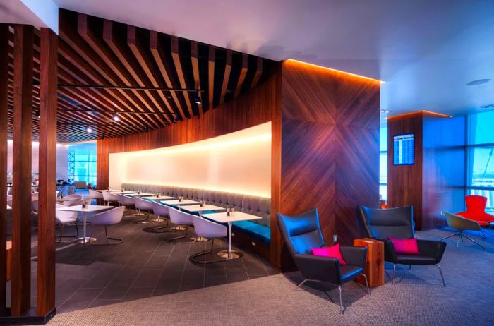 American Express Centurion Lounge dining area in Las Vegas, featuring a row of empty chairs arranged around small white square tables and a banquette.