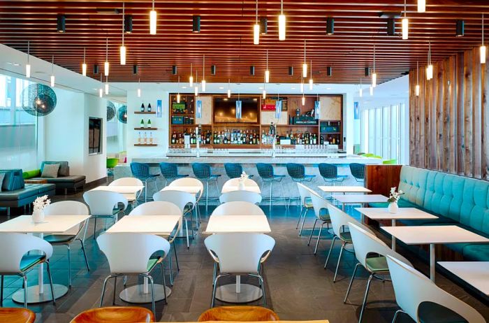 The dining area at the American Express Centurion Lounge in Philadelphia, featuring rows of sleek white chairs and small square tables under soft hanging lights