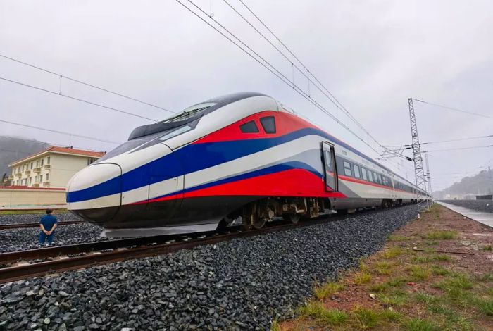 The new train is adorned with stripes of white, red, and blue, reflecting the colors of the Laotian flag.