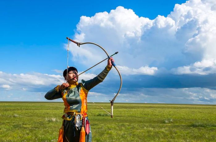 A female archer strikes a pose at a smaller Naadam festival held at the Three Camel Lodge in the Gobi Desert, Mongolia, on September 1, 2019. (Photo by Alison Wright/Getty Images)