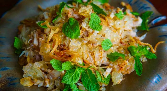 Nhoam krauch thlong: A zesty blend of tangy pomelo, savory pork belly, and sweet toasted coconut.