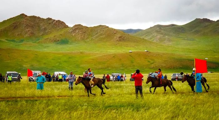 The first jockeys cross the finish line during the Naadam horse races in Uliastai, Western Mongolia. In this traditional Mongolian festival, children as young as 12 participate in races that stretch over 40 kilometers, marking an important rite of passage for young Mongolians. (Photo by Tessa Chan/South China Morning Post via Getty Images)