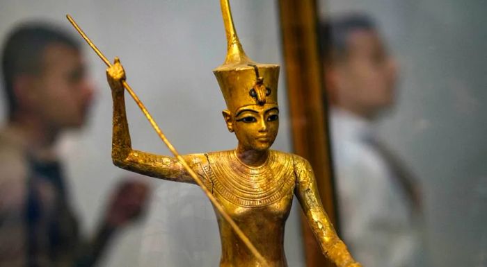 A golden statue of Tutankhamun is depicted holding a harpoon.