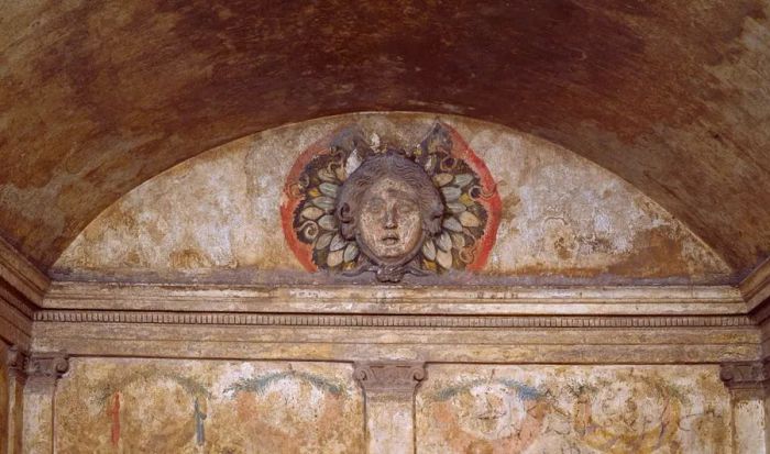 In one tomb, a gorgon gazes down upon the deceased.