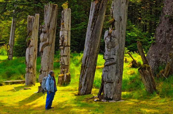 A visitor to Gwaii Haanas National Park in Haida Gwaii observes the Haida mortuary poles.