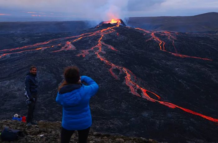 Tourists observe the Fargradalsfjall volcano erupting with molten lava on August 19, 2021, near Grindavik. Iceland is working to prioritize safety for tourists exploring its unpredictable terrain.