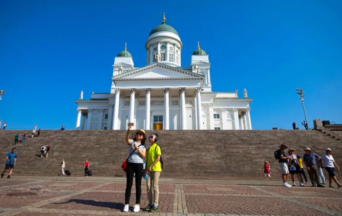 Tourists snap a selfie with the Helsinki Cathedral in the background. Finland is using humor and rhymes to convey key messages to visitors.