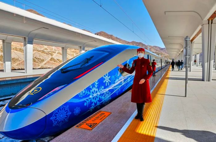 A train attendant stands next to an 'intelligent' Fuxing bullet train on January 6, 2022, in China.