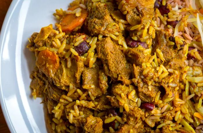 A serving of Jamaican curried goat, accompanied by the traditional rice and peas.