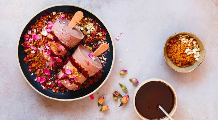 This masala chai kulfi is topped with biscuit crumbles, a drizzle of chocolate syrup, and a sprinkle of dried rose petals.