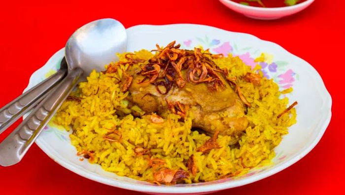 Kao mok gai, a Muslim-inspired dish akin to biryani, features rice cooked in flavorful chicken stock with a blend of saffron, turmeric, cardamom, and bay leaves.