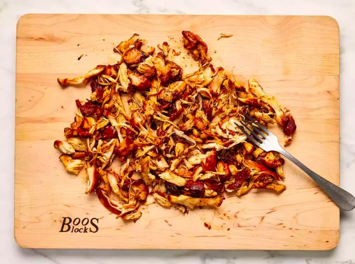 Shredded chicken resting on a wooden cutting board