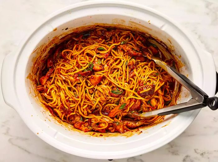 Noodles, shredded chicken, and scallions mixed together in the slow cooker