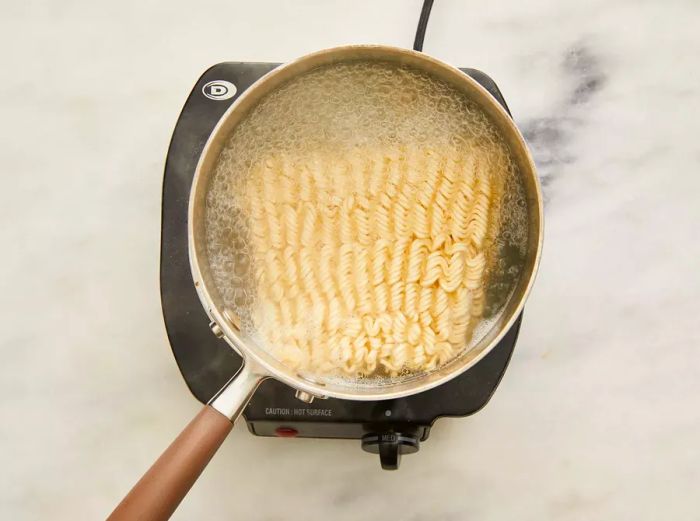 A pot of boiling water with ramen noodles added.