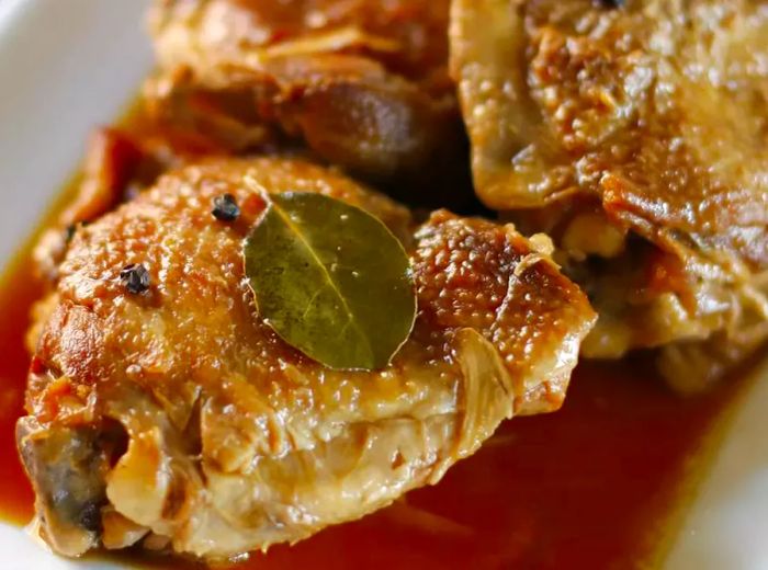 Close-up of Chicken Adobo garnished with a bay leaf on a plate