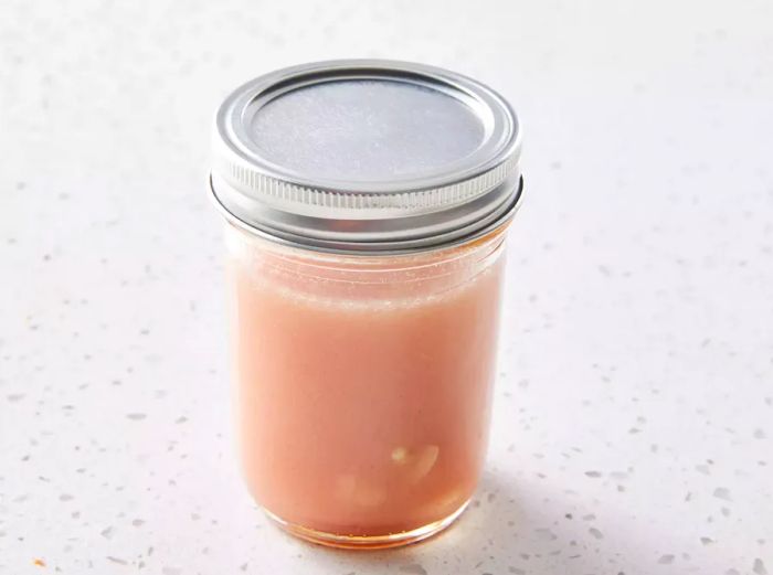 Vinegar, vegetable oil, crushed garlic, and Dijon mustard mixture in a glass jar