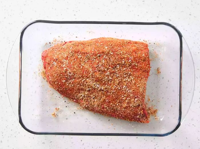 Tri-tip beef coated with spice rub in a glass baking dish