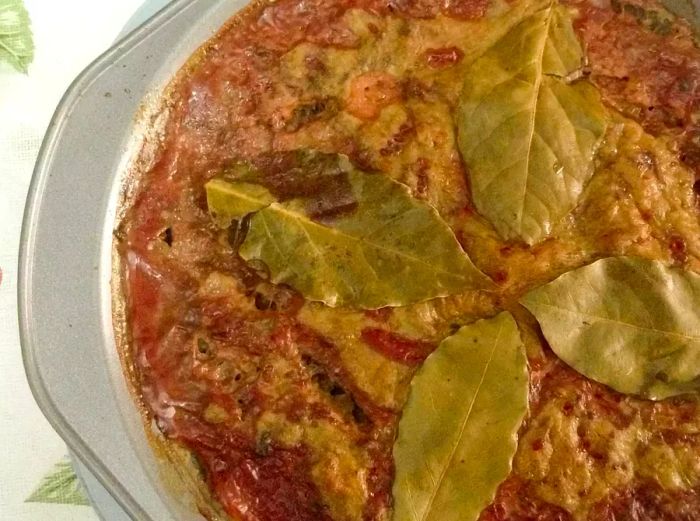 close-up of Pork Liver Pudding garnished with bay leaves in a baking dish