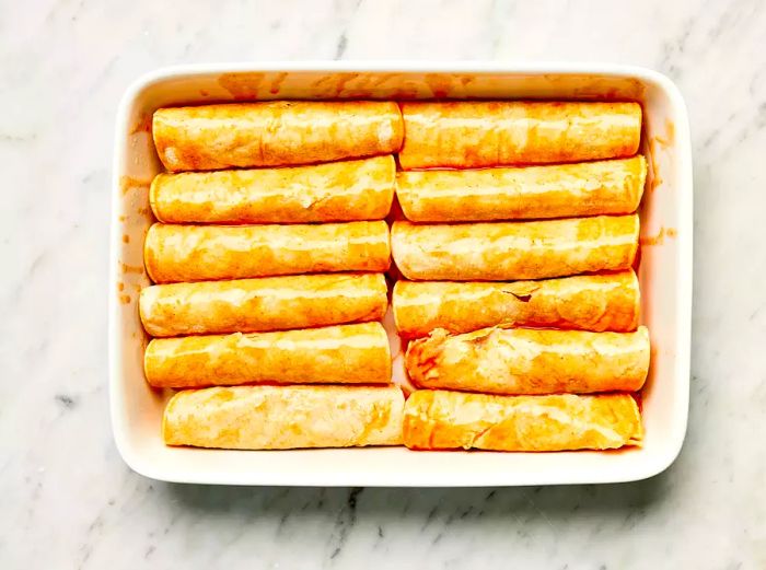 Refried Bean and Cheese Enchiladas in a white casserole dish