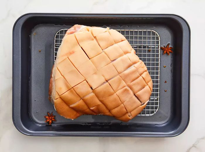 Top-down view of a raw roast resting on a wire rack placed on a baking sheet.