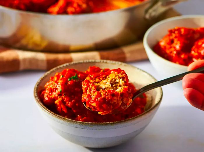 Porcupine meatballs served on a spoon over a bed of rice, ready to enjoy.